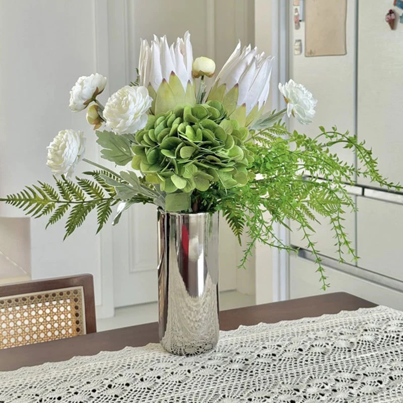 Spiegelnde hohe zylindrische dekorative Metallvase mit künstlicher Hortensie und Protea Arrangement