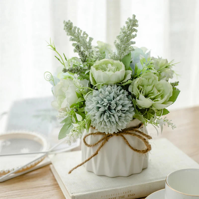 Seidenblumenarrangement in einem mit Schnur umwickelten Keramikpflanzer als Tischmittelpunkt