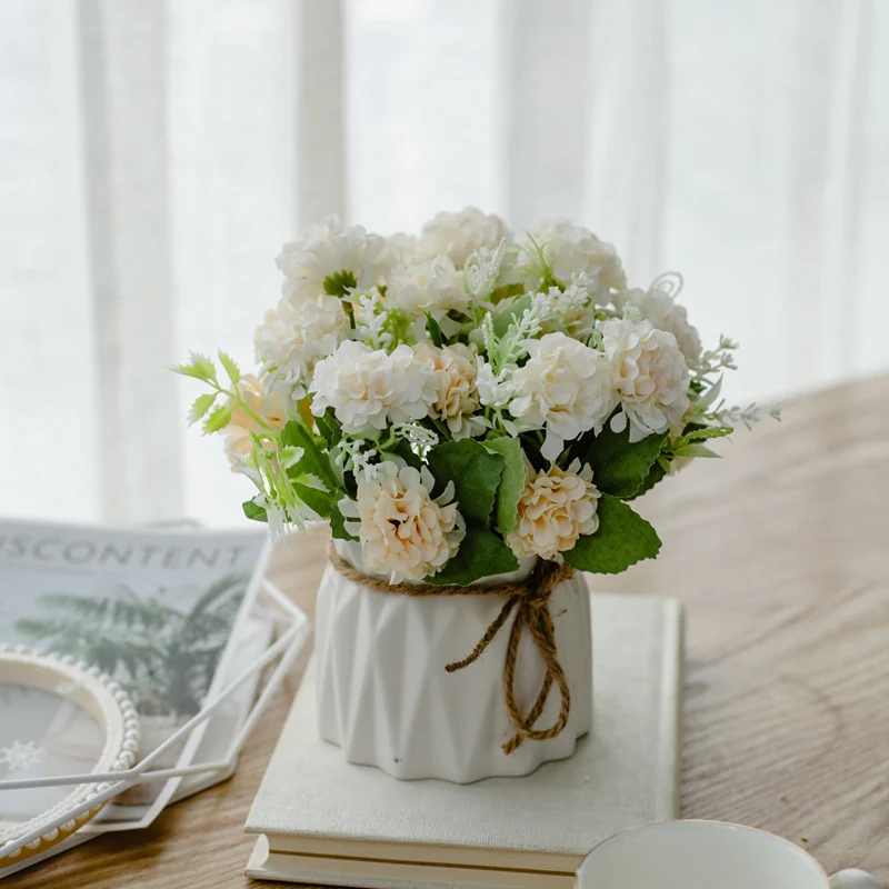 Seidenblumenarrangement in einem mit Schnur umwickelten Keramikpflanzer als Tischmittelpunkt