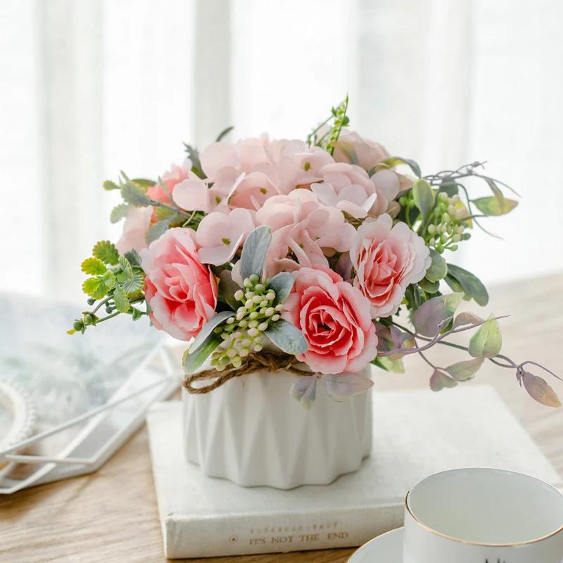 Seidenblumenarrangement in einem mit Schnur umwickelten Keramikpflanzer als Tischmittelpunkt