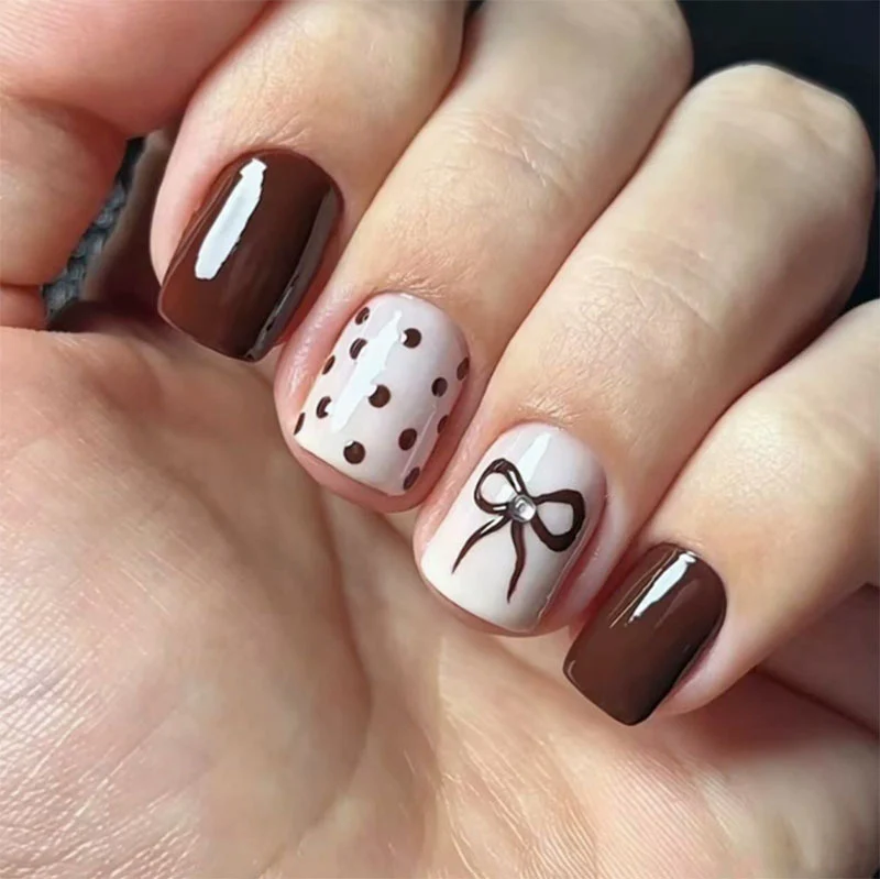 Dekorative Press-On Nageldesign mit Schleife und Punkten