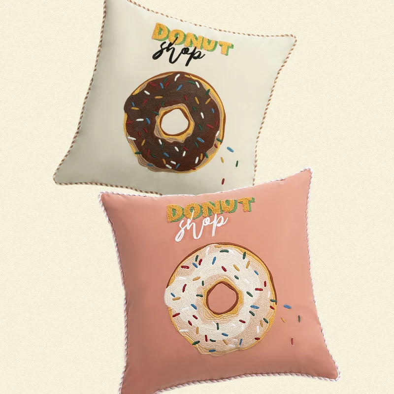 Quadratisches Dekokissen mit gesticktem Donut-Motiv und dekorativer Kederkante