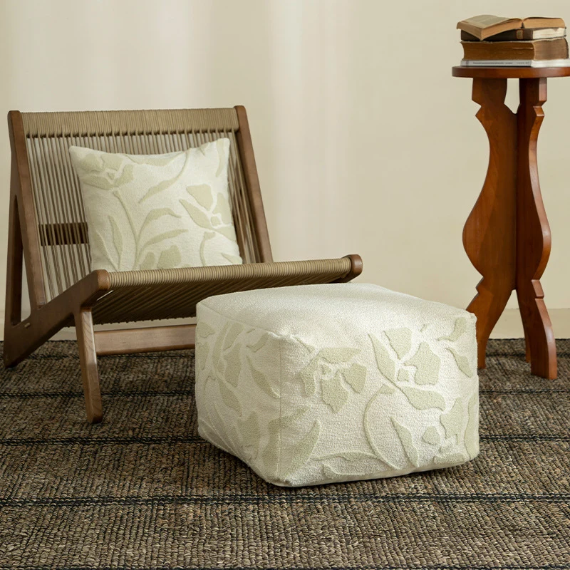 Quadratischer Bodensitzpouf mit strukturierter Bouclé‑Oberfläche und floralem Relief